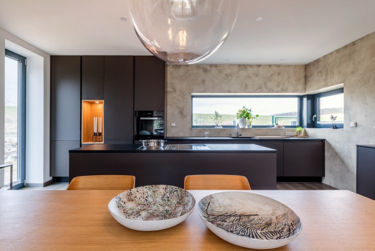 A stylish living space with a modern kitchen and complementing Merano chair and armchair