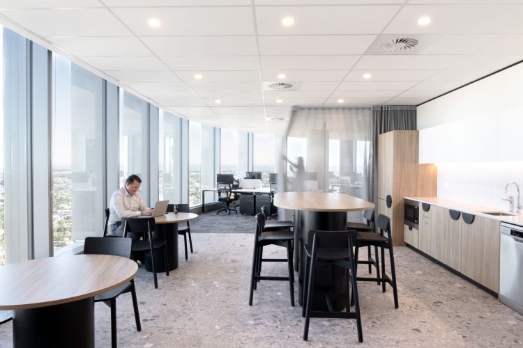 A modern office setup showcasing sleek black wooden furniture beside large windows, providing panoramic city views