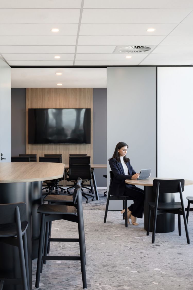 A modern office space with black wooden chairs and stools