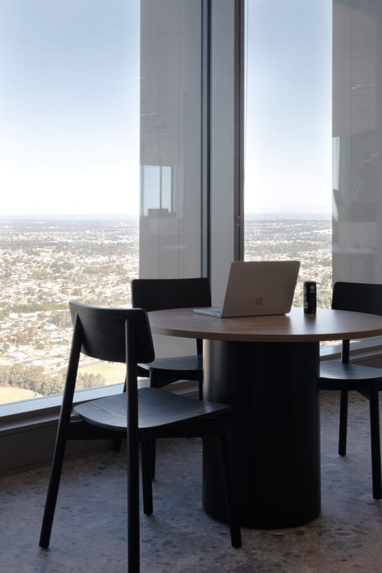 Black wooden chairs and a table next to big windows