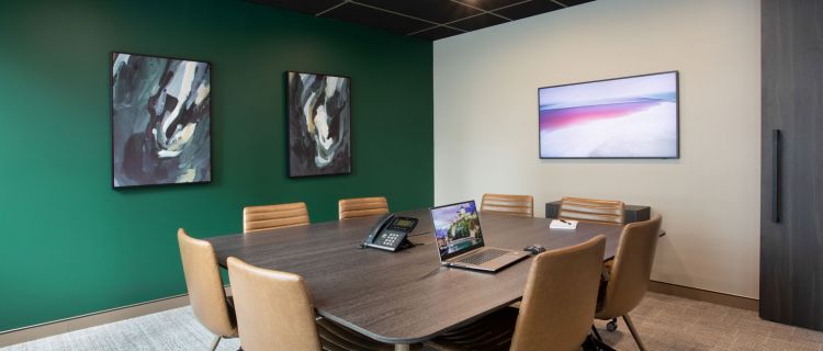 An office meeting room featuring a green wall with office chairs and a table