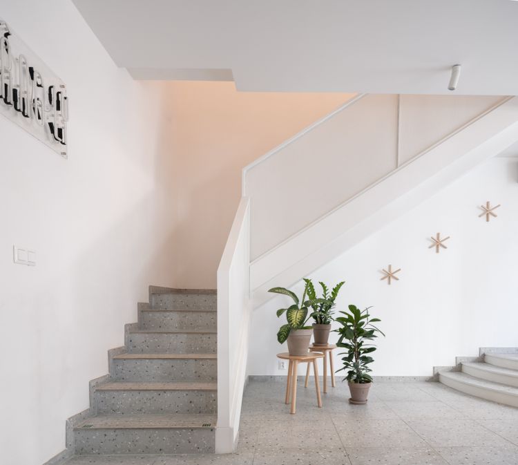 A staircase provides access to the upper level, next to the stairs is the wall featuring minimalist wooden star-shaped decorations.