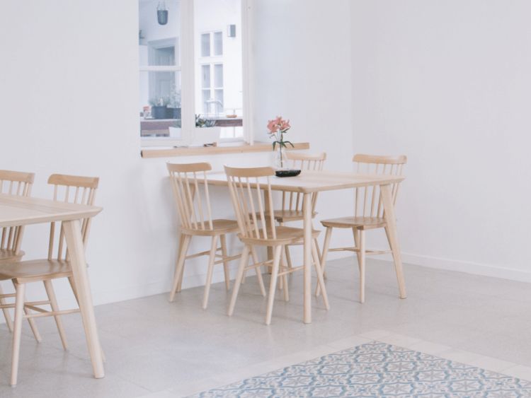 Minimalist café interior with a white dominant color scheme, featuring a table surrounded by natural wooden dining chairs