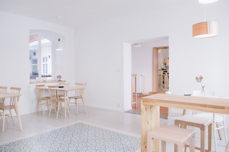 Large arched windows flood the space with natural light, highlighting the wooden dining tables surrounded by matching chairs.