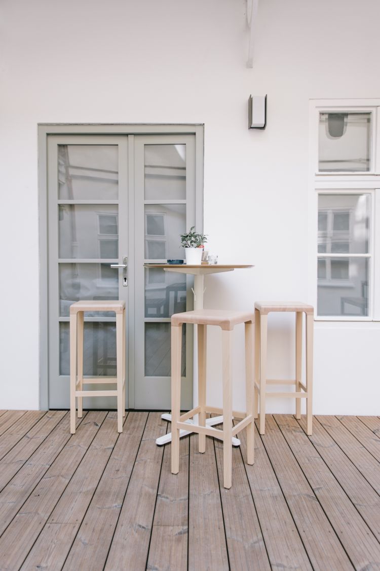 A table surrounded by three stools next to the window
