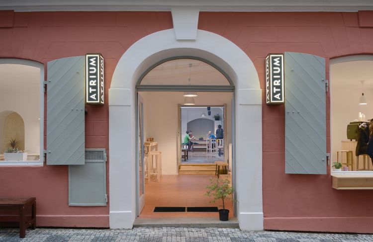 The entrance to Café Atrium, framed by a large white archway set against a soft coral-colored façade. 