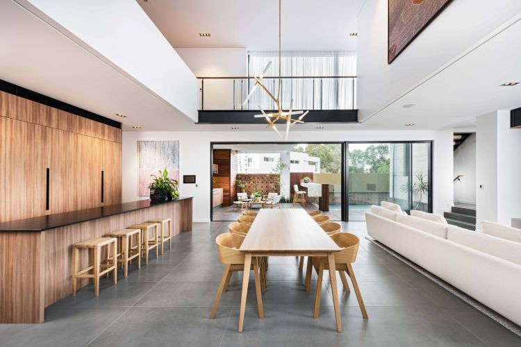 Modern open-concept living space featuring a sleek wooden kitchen island with bar stools, a spacious dining area with a wooden table and chairs, and a comfortable lounge area.