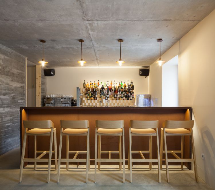 Modern bar setup with a rustic touch, featuring a brown counter lined with four Merano wooden bar stools