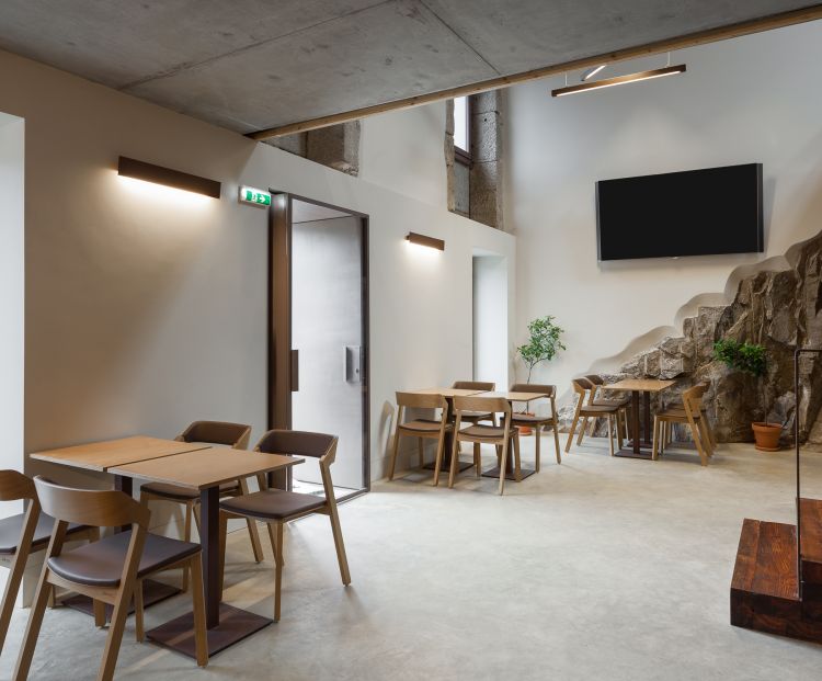 Contemporary dining area with wooden tables and chairs set on a polished concrete floor.