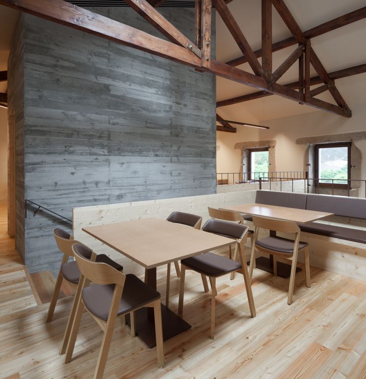 Rustic dining space with exposed wooden beams on the ceiling, complemented by a weathered wood wall.