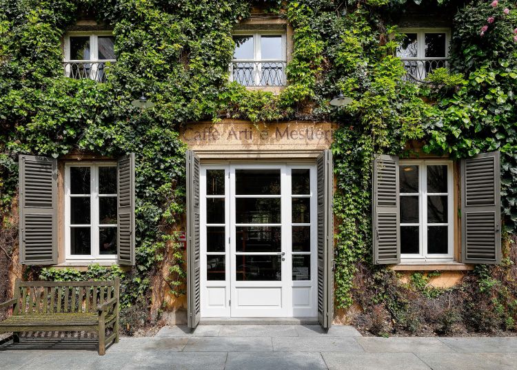 Charming exterior of Caffè Arti e Mestieri, with the building's façade covered in lush green ivy