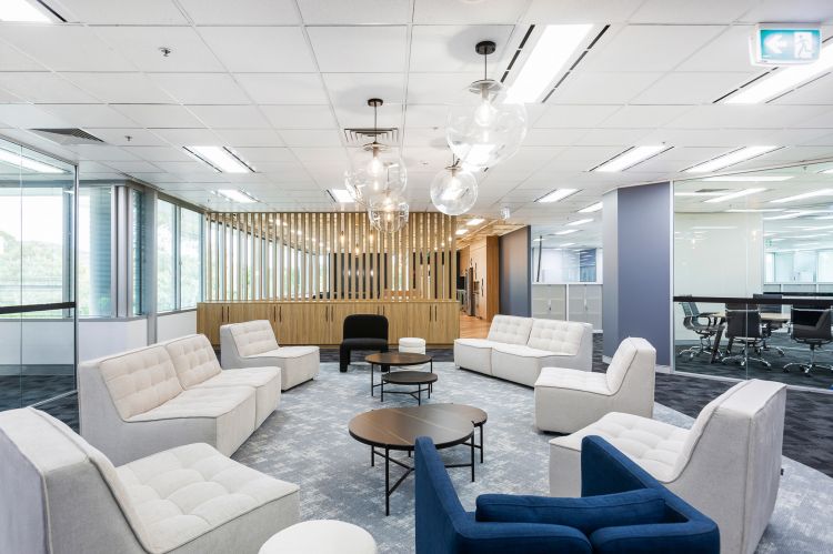 Modern office lounge area with large floor-to-ceiling windows providing natural light.