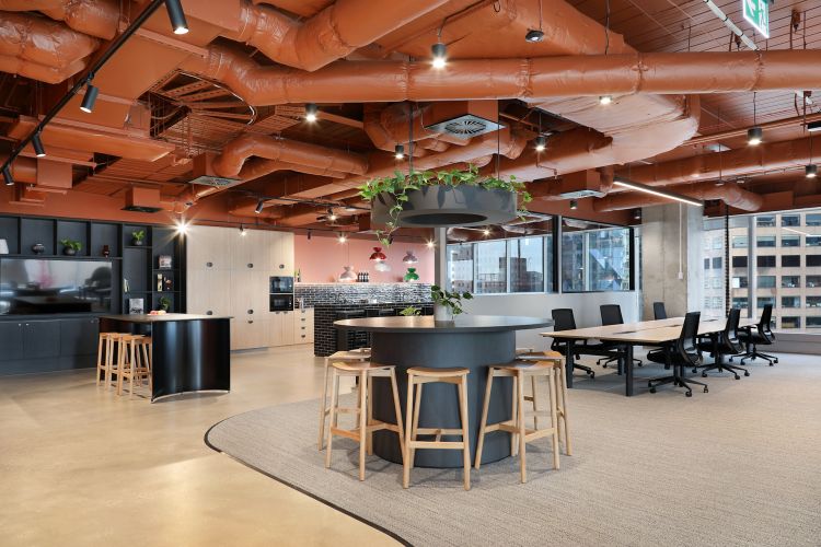 Modern office space featuring exposed terracotta-colored ductwork overhead