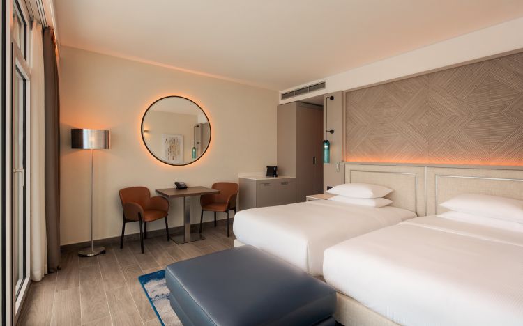 Modern hotel room featuring twin beds with a geometric headboard design