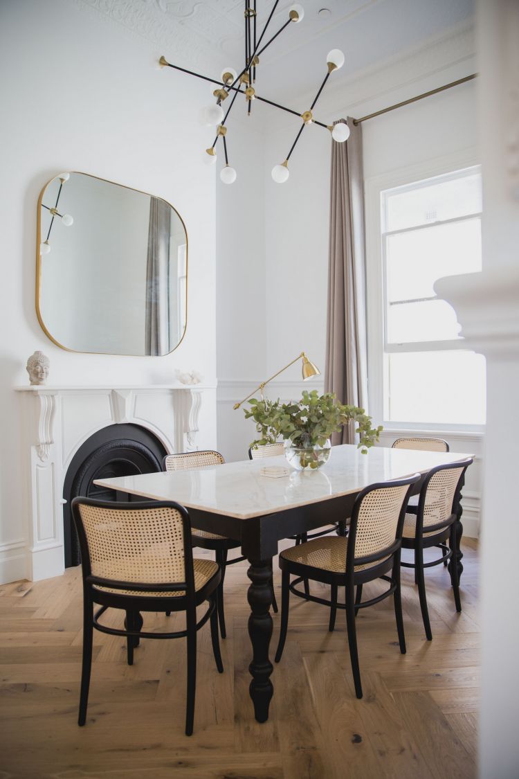 Elegant dining room with a bright atmosphere, showcasing a large oval gold-framed mirror