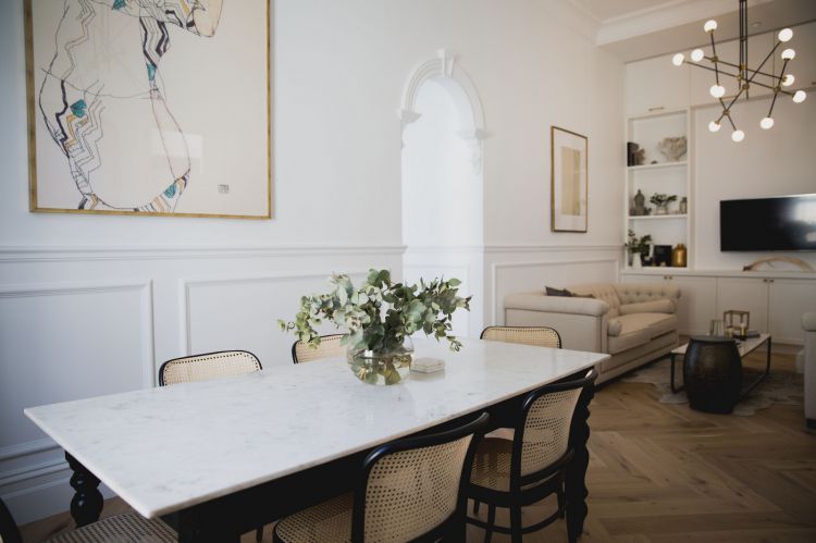 Elegant interior of a living space featuring a white marble dining table surrounded by cane-back chairs.