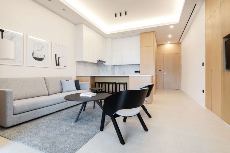 Modern living room with a light gray sofa, black and white cushioned chairs, and a round coffee table.