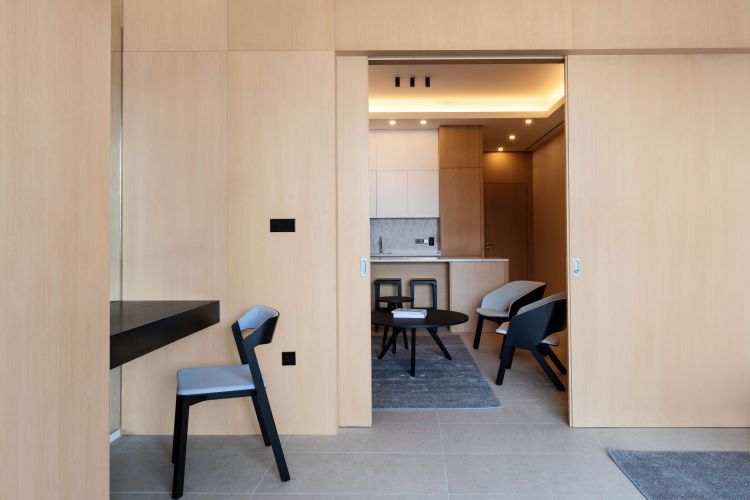 Modern minimalist room featuring light wood-paneled walls, a sleek black side table with a matching chair