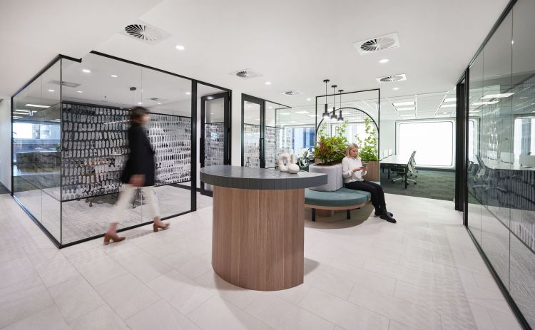 Bright and contemporary office space featuring clear glass partitions and a unique wall design resembling brush strokes