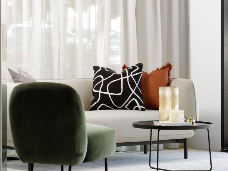 Contemporary living room corner featuring a light beige sofa adorned with various pillows