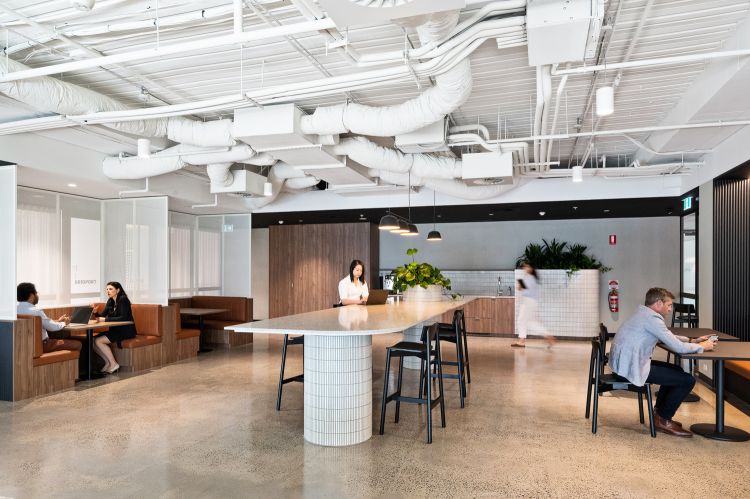 Modern office space with exposed white ventilation ducts overhead. 