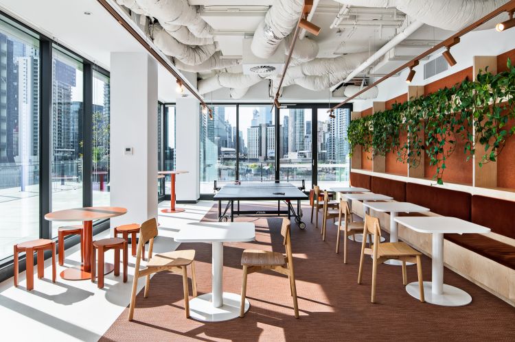 Bright office lounge with floor-to-ceiling windows showcasing a city view