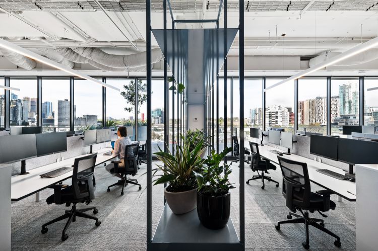 Spacious open-plan office featuring large floor-to-ceiling windows that offer a panoramic view of a city skyline.