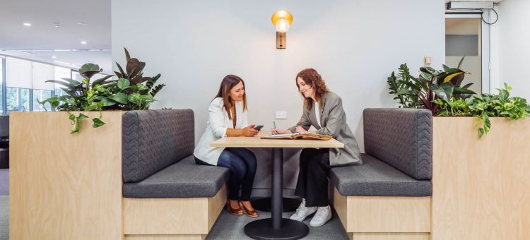 Two women in a modern office sitting area discussing