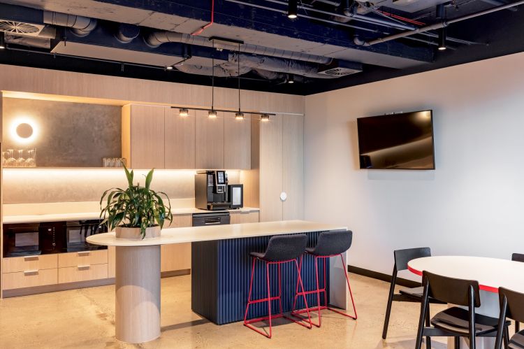 A modern, industrial-style kitchen and dining area in an office. 