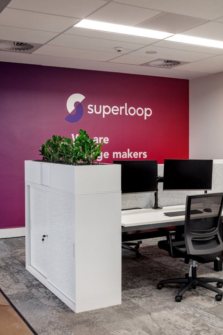 A well-organized office space featuring a vibrant purple wall with the Superloop logo