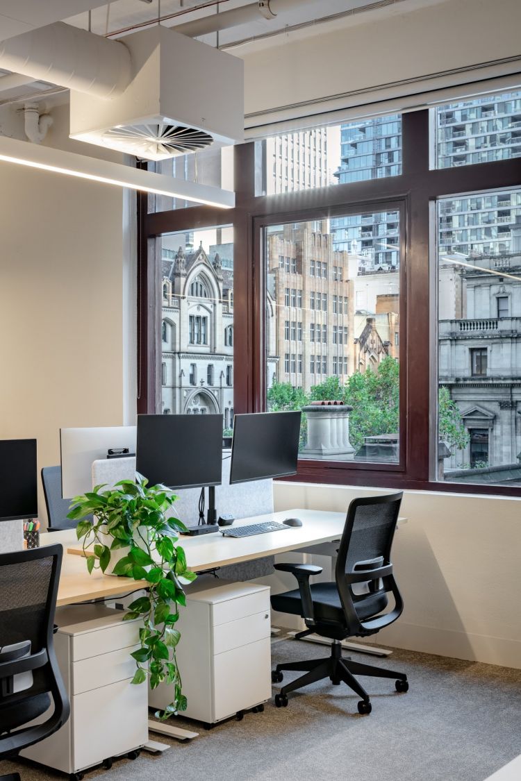 An office workspace beside a large window that offers a view of historic buildings.