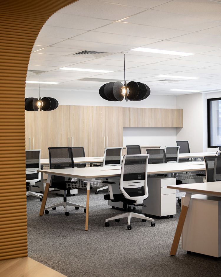 A modern and bright office space viewed through a wooden archway. 