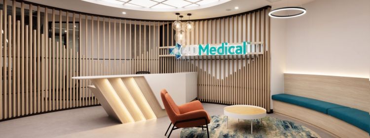 A panoramic view of a modern office reception area with wooden slat walls, a white reception desk with a slanted design