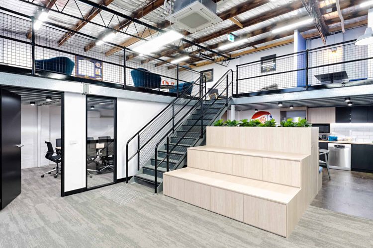 Cozy office lounge area with colorful chairs, a red beanbag, and industrial ceiling elements.