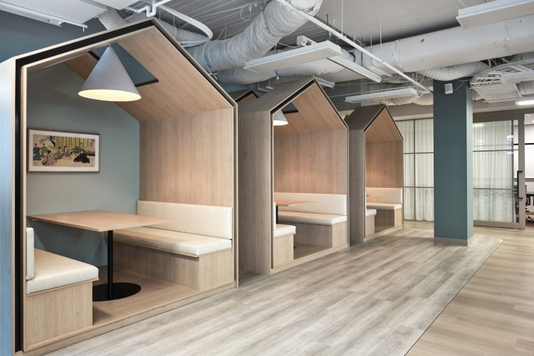 Modern office nooks with house-shaped wooden booths, pendant lighting, and artwork.