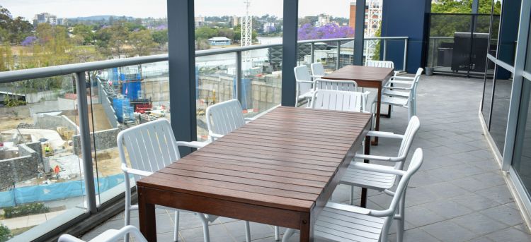 Outdoor balcony area with a wooden table and white Roku armchairs