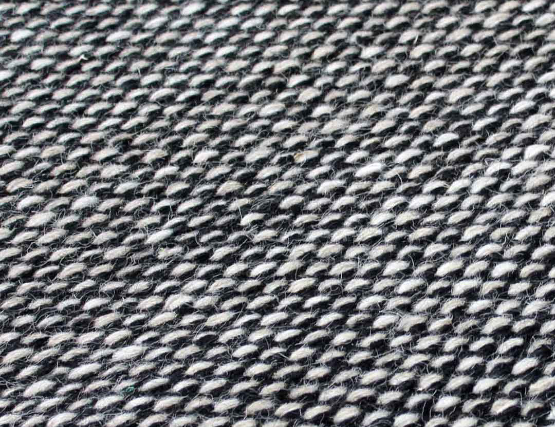 Subi Wool Rug Black Beige. Detailed image of low profile flatweave rug with cream and black marle