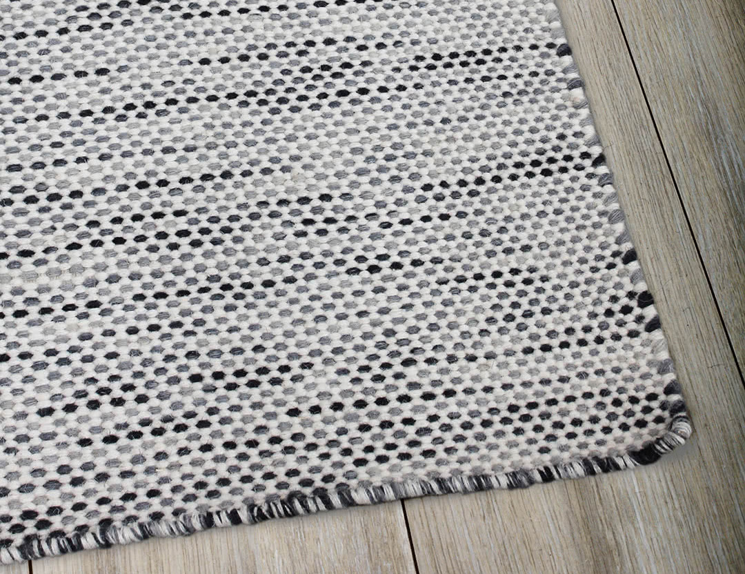 Subi Wool Rug Charcoal Ivory. Detailed image of low profile flatweave rug in grey with cream and black marle