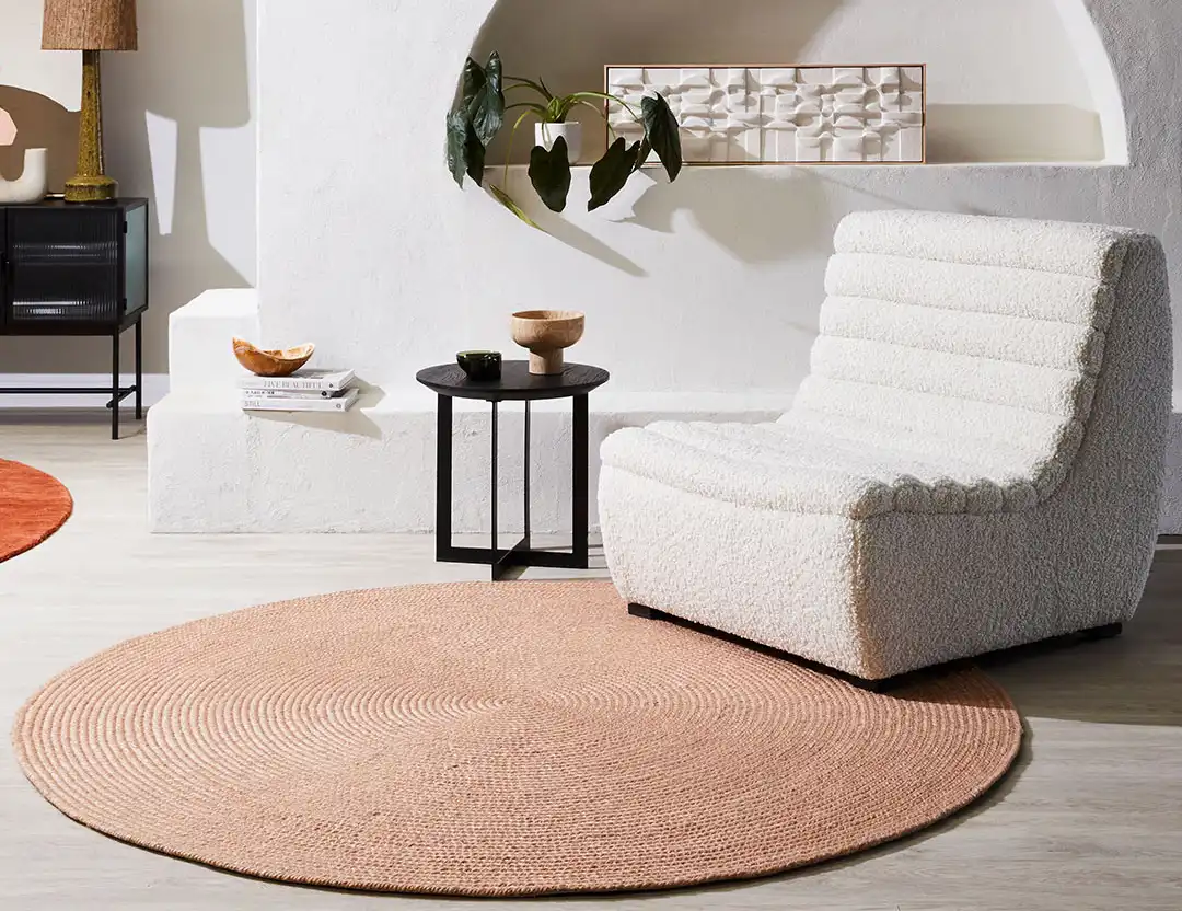 Paddington round wool rug in pink clay with beige longe chair and black table
