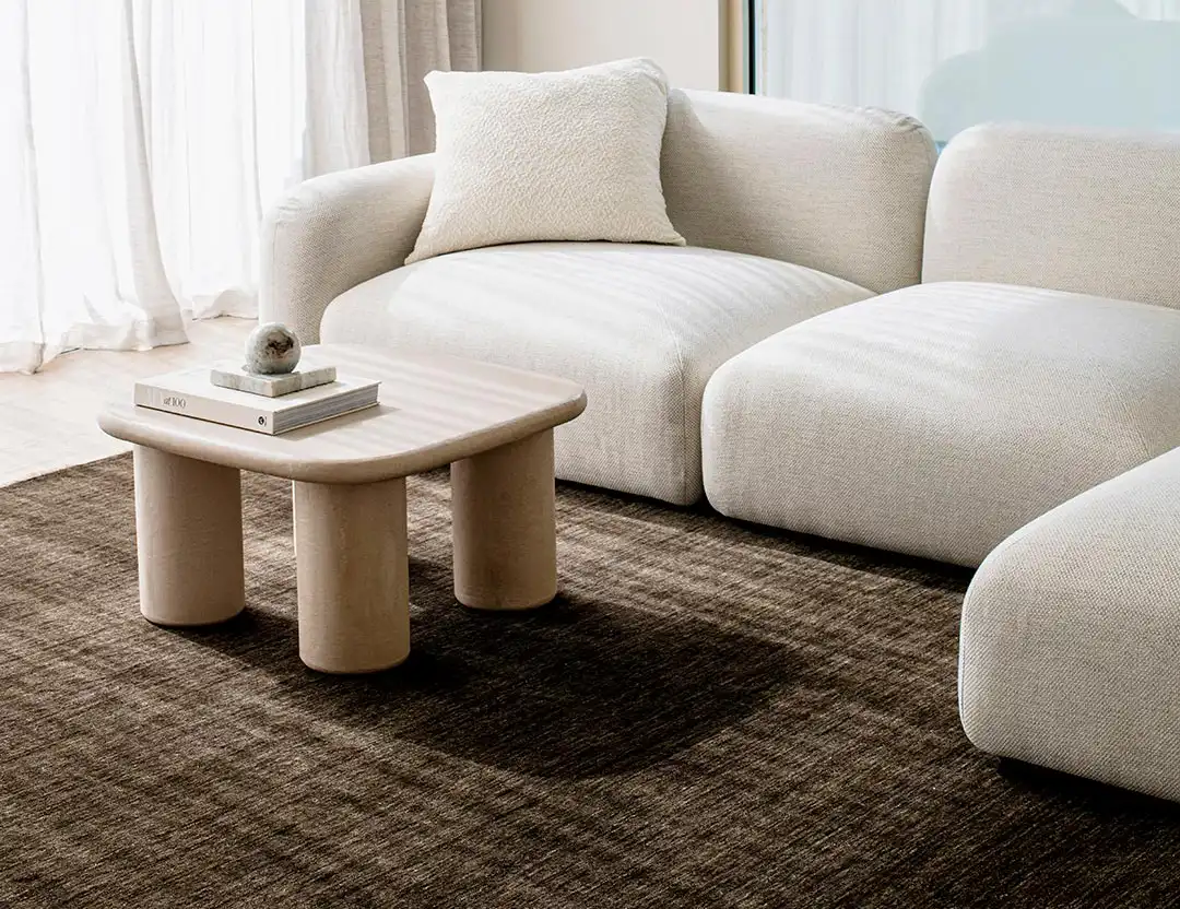 Diva Fringed Wool Rug in espresso brown with rounded wooden coffee table and beige lounge