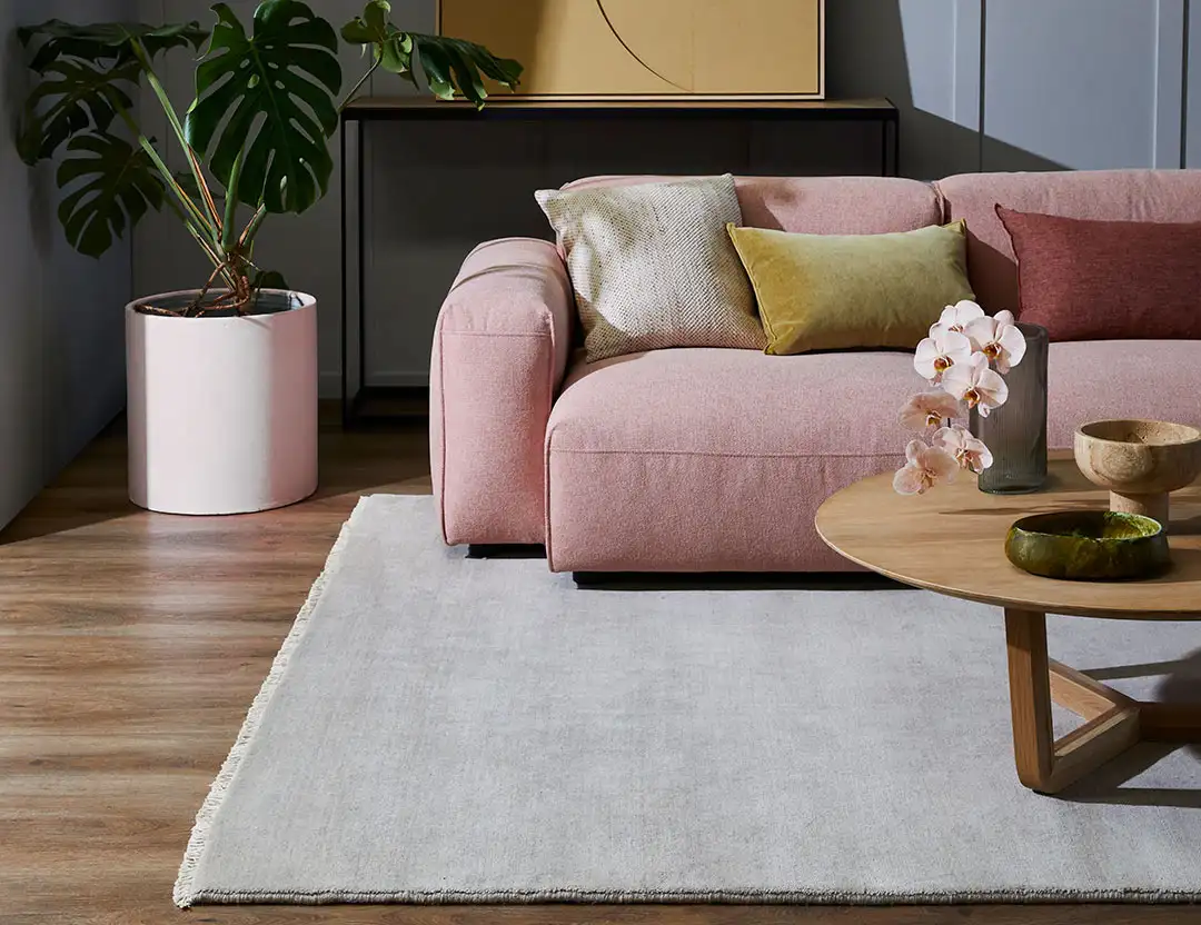 Diva Fringed Wool Runner in Moonstone grey with blush pink sofa and timber coffee table with a orchids