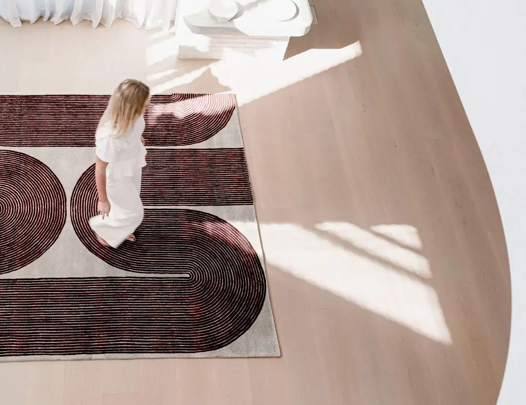 woman walking across the room on a Viper wool rug in Currant with geometric swirl pattern