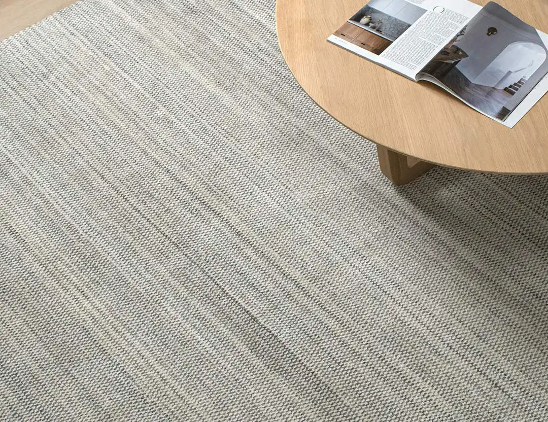 Mystique Wool Rug in Grey Ivory Marle with an oak coffee table and open magazine