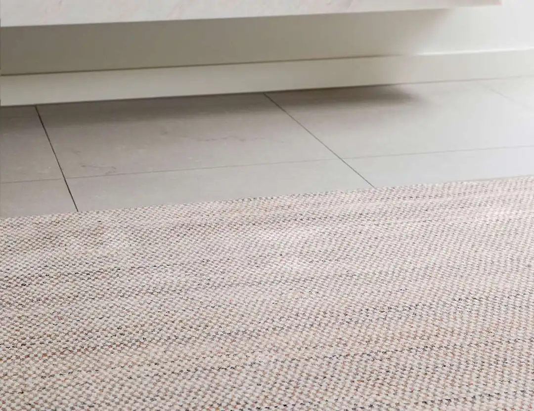 Mystique Wool Rug in Rust Ivory marle on beige stone tiles by a stone mantle