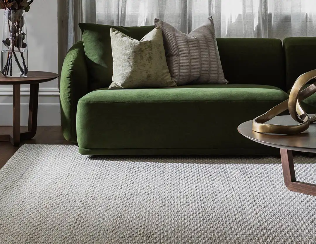 Marco Wool Rug in Ice beige with a green sofa and brass coffee table