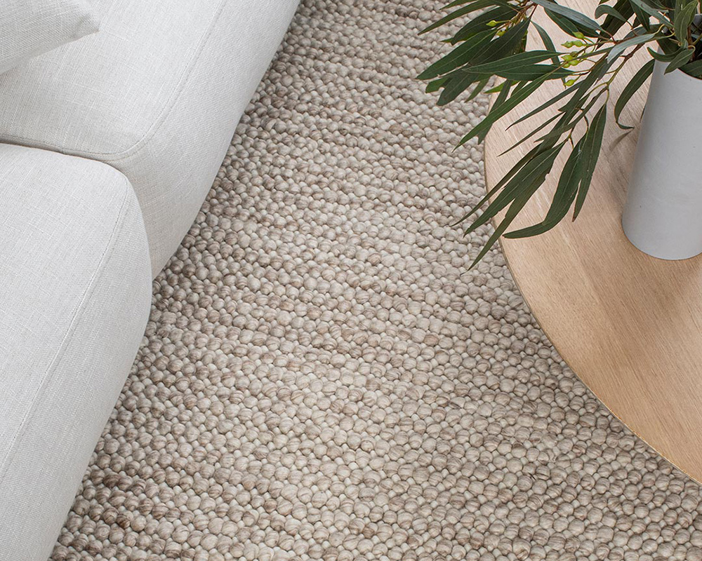 Magic Rug in Linen. Textured wool rug in neutral cream and brown tones with natural coffee table.