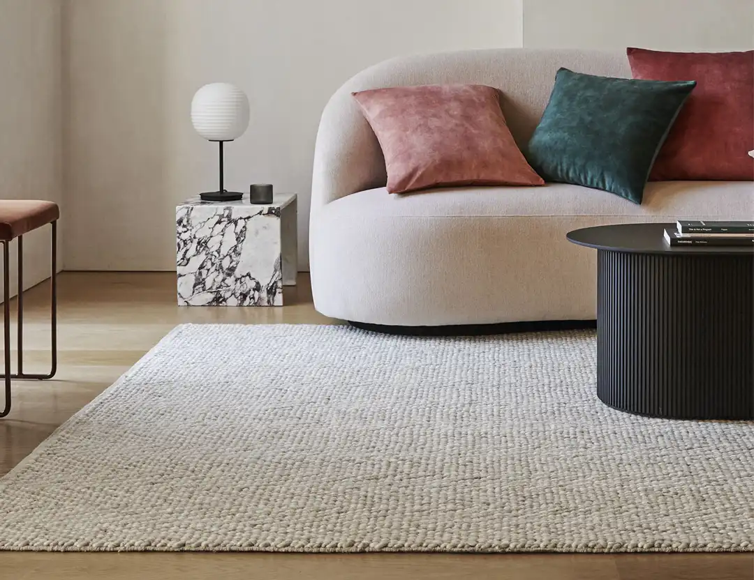 Zambesi Wool Blend Rug in Sandstorm beige with beige sofa, velvet cushions and black coffee table